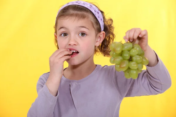 Malá holčička jíst hrozny. — Stock fotografie