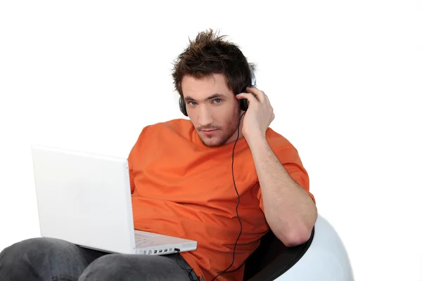 Νεαρός άνδρας που ακούτε μουσική μέσω του φορητού υπολογιστή — Φωτογραφία Αρχείου