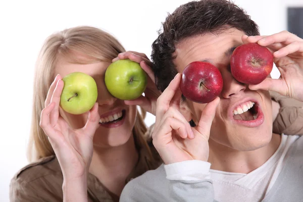 Pareja tirando caras tontas con manzanas — Foto de Stock