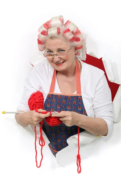 Ηλικιωμένη γυναίκα, φορώντας μαλλιά οδοστρωτήρες, ενώ πλέξιμο — Φωτογραφία Αρχείου