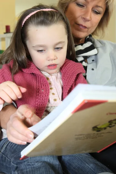 Klein meisje het lezen van een boek met haar oma — Stockfoto