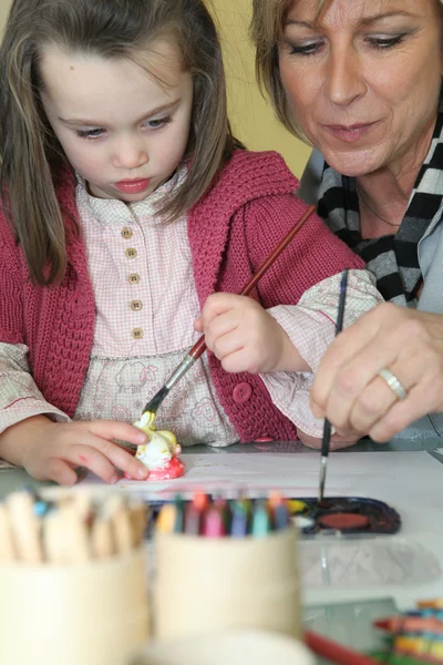 Mujer pintando con una chica joven — Foto de Stock