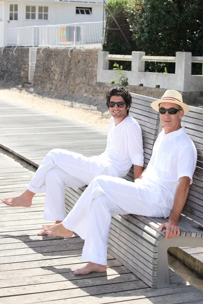 Мужчины сидят на скамейке в солнечный день — стоковое фото