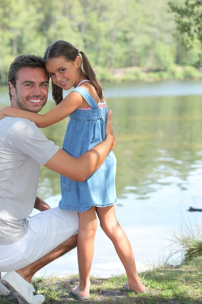 Padre e hija de pie en una orilla del río —  Fotos de Stock