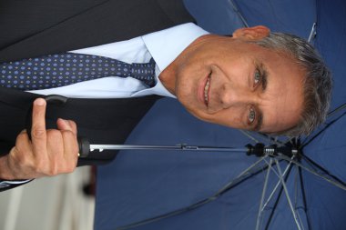 Businessman holding an umbrella clipart