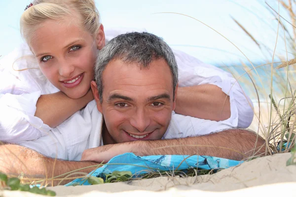 Couple laid together on beach — Stock Photo, Image