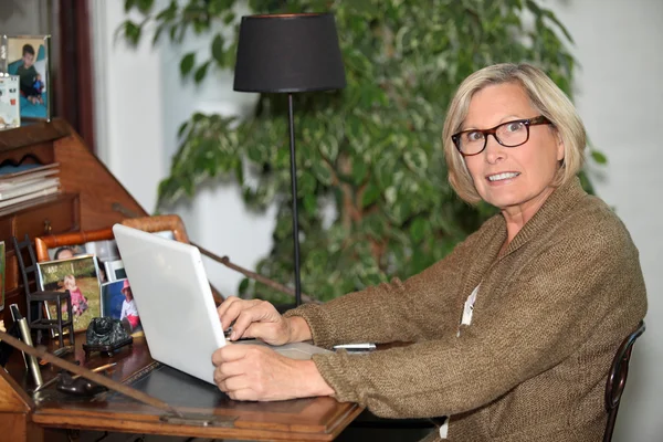 Vrouw die op haar laptop thuis werkt — Stockfoto