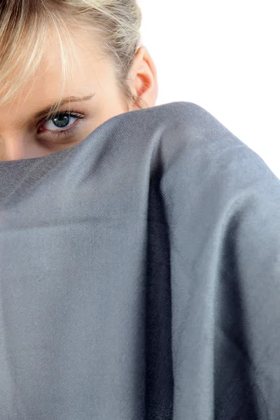 Девушка прячется за серым шарфом — стоковое фото