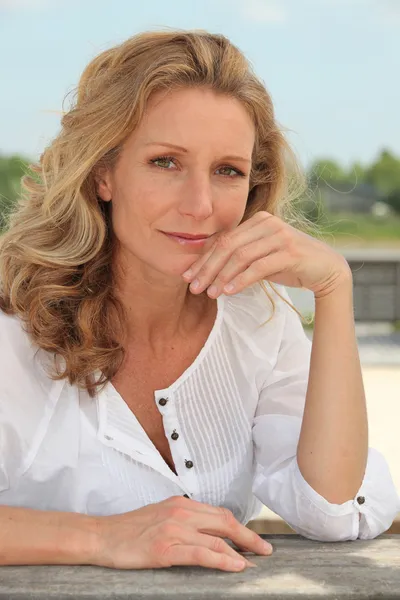 Femme réfléchissante avec de longs cheveux blonds assis à l'extérieur — Photo