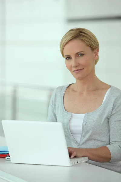 Mulher trabalhando em um computador portátil branco — Fotografia de Stock