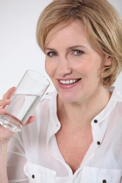 Μια μέση ηλικία γυναίκα έχοντας ένα ποτήρι νερό. — Φωτογραφία Αρχείου