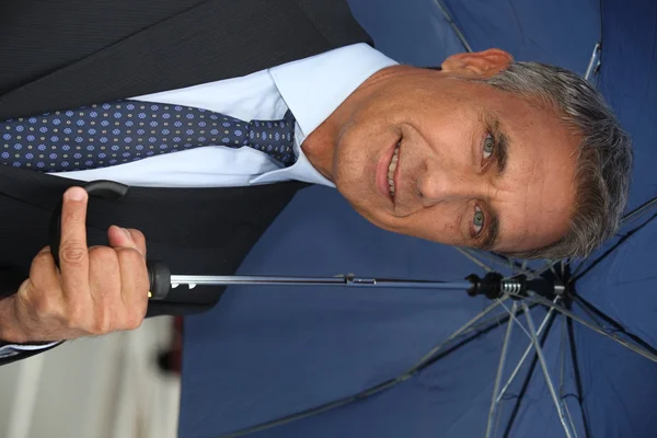 Бизнесмен, держащий зонтик — стоковое фото
