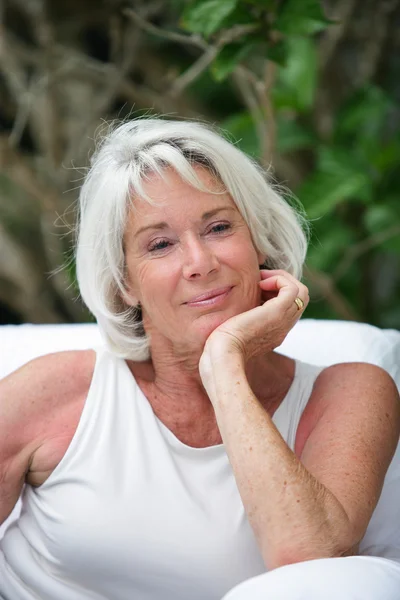 Older woman sitting out in a garden — Stock Photo, Image
