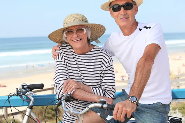 Старша пара катається на велосипедах біля океану — стокове фото