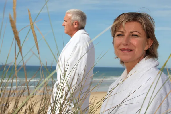 Ένα ώριμο ζευγάρι φορώντας μπουρνούζι στην παραλία. — Φωτογραφία Αρχείου