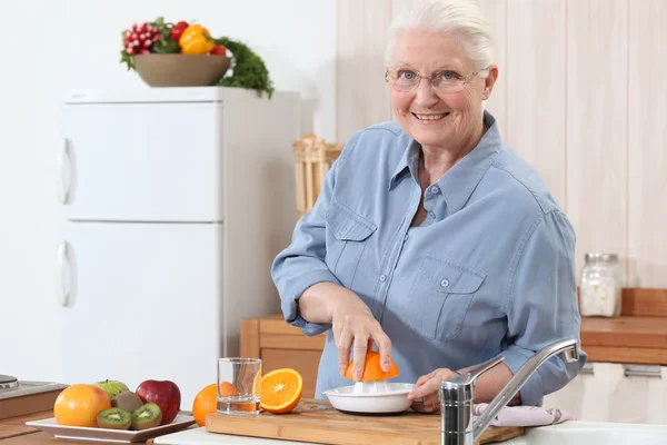 Een oude dame te drukken sinaasappelen. — Stockfoto