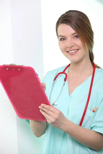 Медсестра дивиться на буфер обміну посміхається — стокове фото