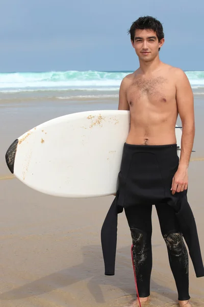 Мальчик-подросток на пляже держит доску для серфинга — стоковое фото