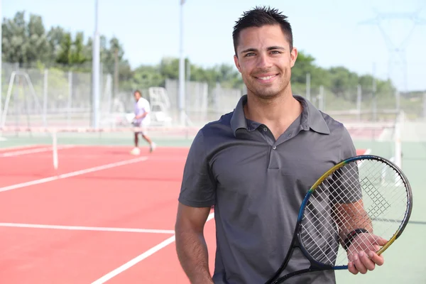 Giocatore di tennis in posa davanti a un campo da tennis — Foto Stock