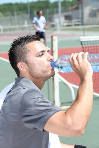 Jugador de tenis bebiendo en el banco — Foto de Stock