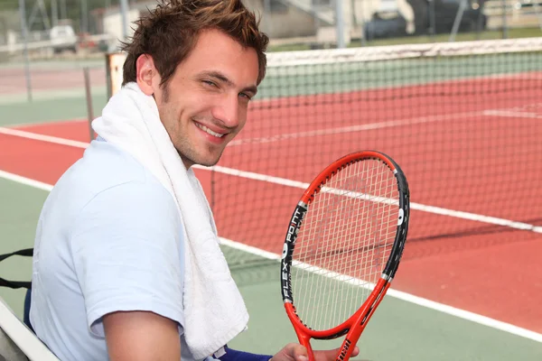 Young tennis player sitting on the court sidelines — Stock Photo, Image