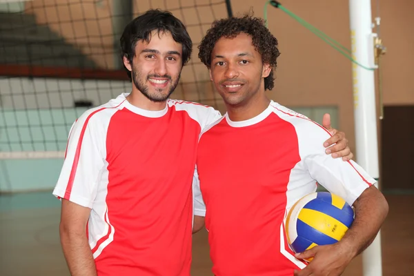 Члены команды стояли с волейбольным мячом на крытой площадке — стоковое фото