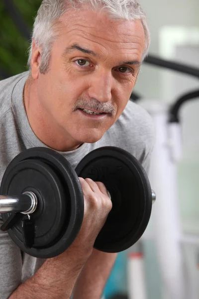 Mann hebt eine Hantel im Fitnessstudio — Stockfoto