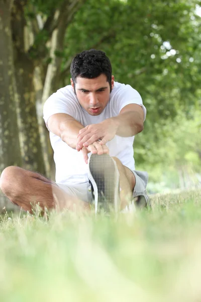 Runner stretching on grass — Stock Photo, Image