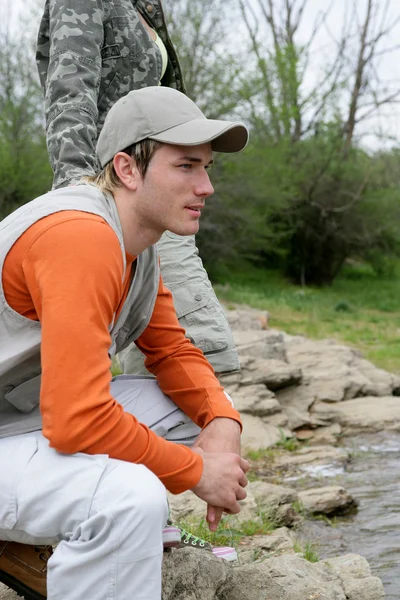 Человек, сидящий на берегу реки — стоковое фото