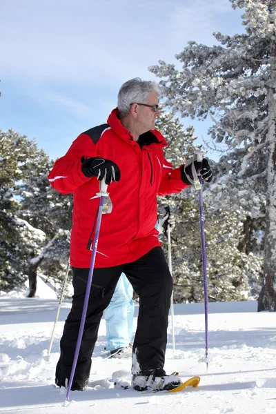 Older man walking in snow shoes — Stock Photo, Image