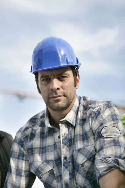Trabajador de la construcción en una camisa a cuadros y casco — Foto de Stock