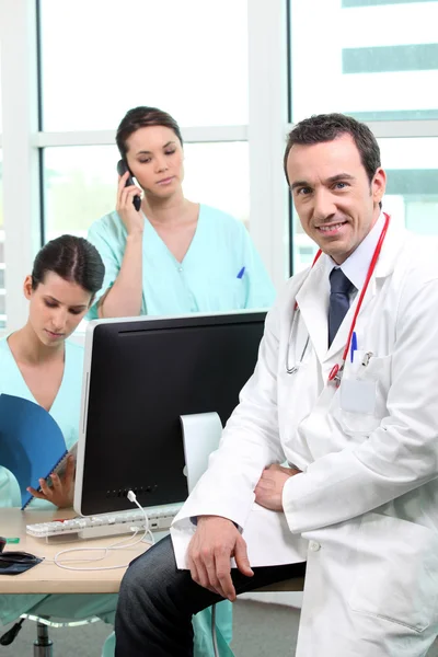 Doctor sitting with nurses at a computer — Stock Photo, Image