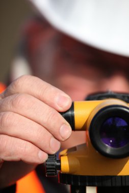 Civil engineer adjusting a theodolite clipart