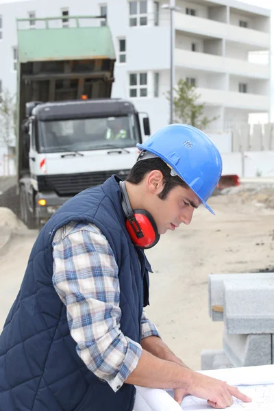Pracownik budowlany patrzy na plany — Zdjęcie stockowe