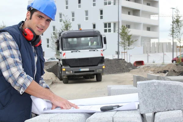 Young foreman outdoors with plan amid cobblestones — Stock Photo, Image