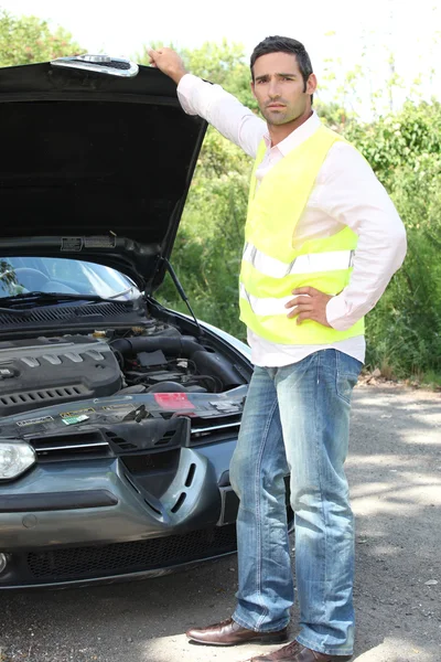 Человек в куртке с высокой видимостью стоял, осматривая двигатель автомобиля — стоковое фото