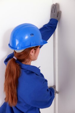 Female worker wearing a blue jumpsuite is checking the wall's straight clipart