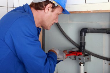 Plumber tightening a joint with a wrench clipart