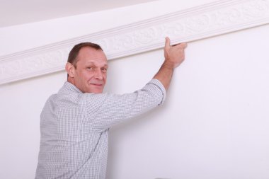 Decorator fixing coving to a ceiling clipart