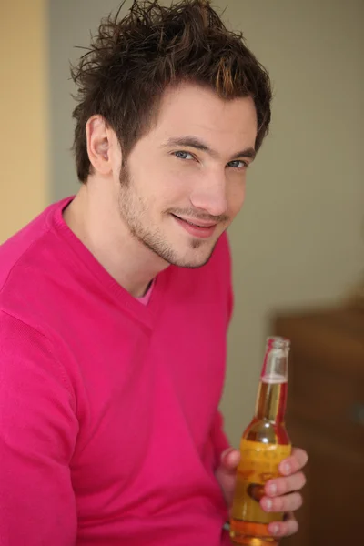 Jeune homme souriant avec bouteille de bière — Photo