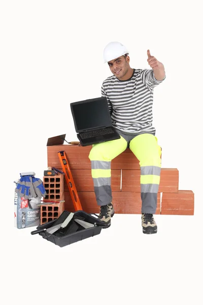 Construtor com um laptop mostrando uma tela em branco — Fotografia de Stock