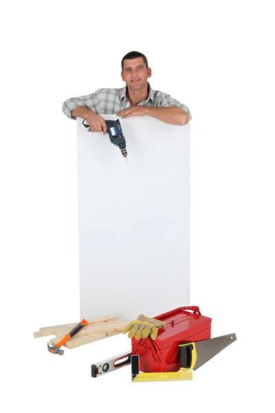 Człowiek posiadający Wiertarka obok panelu puste reklama — Zdjęcie stockowe