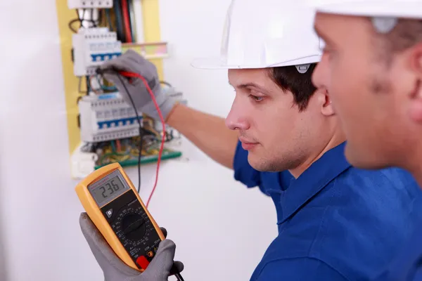 Dos ingenieros técnicos revisando equipos eléctricos — Foto de Stock