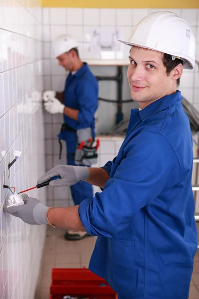 Young electricians wiring wall sockets — Stock Photo, Image