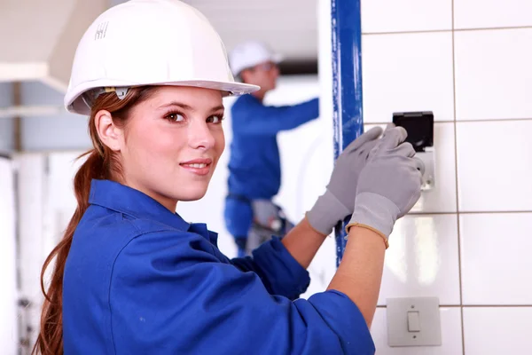 stock image Young female electrician wiring a building