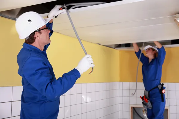 Twee elektriciens herstellen plafond bedrading — Stockfoto