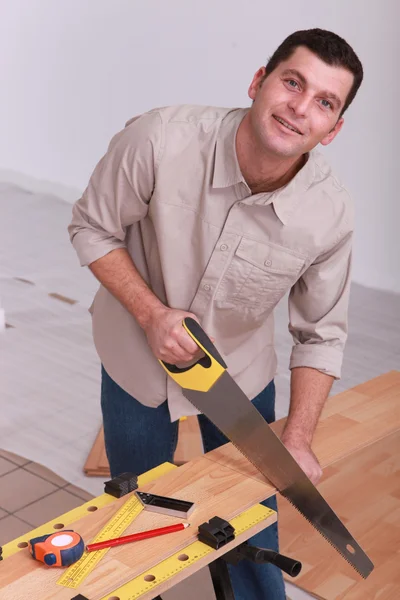 Man sawing wooden floorboards — Stock Photo, Image
