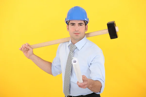 Ingenieur holding een samengevouwen blauwdruk en een hamer — Stockfoto