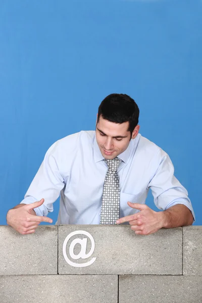 Muž směřující na symbol přilepená ke zdi — Stock fotografie