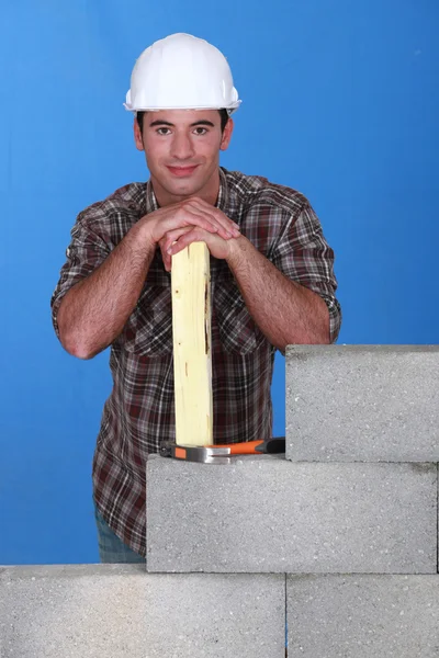Mason stood with plank behind unfinished wall — Stock Photo, Image